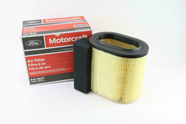 A Motorcraft air filter displayed next to its packaging. The filter is oval-shaped with a yellow pleated design, and the box features red and white branding, indicating it is an air filter (Filtre à air) with the part number FA-1927.